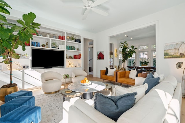 living room featuring ceiling fan, wood-type flooring, and built in shelves