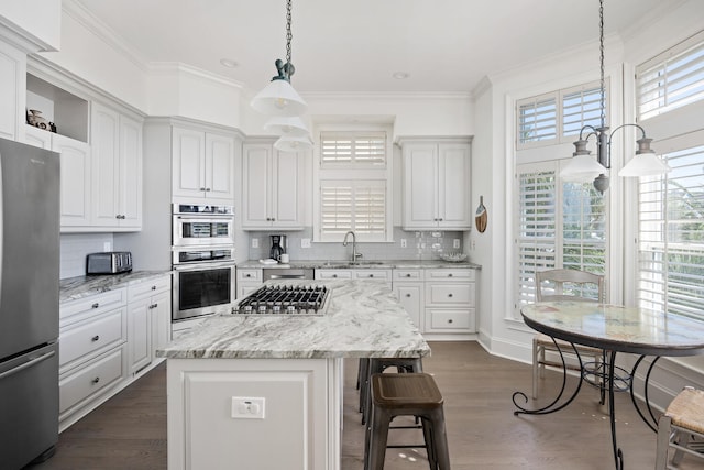 kitchen with white cabinets, appliances with stainless steel finishes, a kitchen island, and dark wood-type flooring