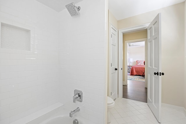 bathroom with toilet, tiled shower / bath combo, and tile patterned flooring