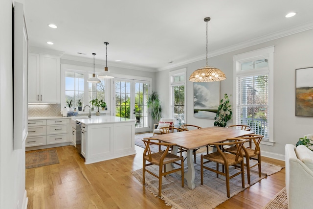 dining space with ornamental molding, plenty of natural light, french doors, and light wood-type flooring