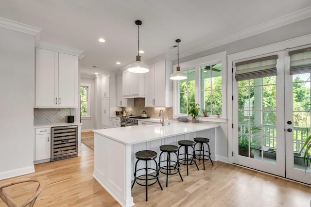 kitchen with ornamental molding, a breakfast bar, beverage cooler, and white cabinetry