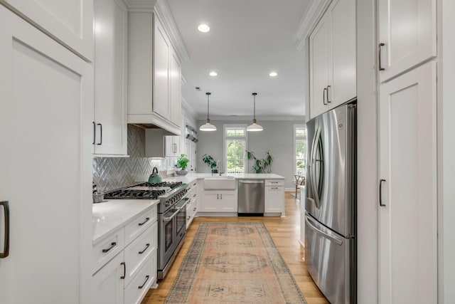 kitchen featuring appliances with stainless steel finishes, light countertops, light wood-style flooring, a peninsula, and tasteful backsplash
