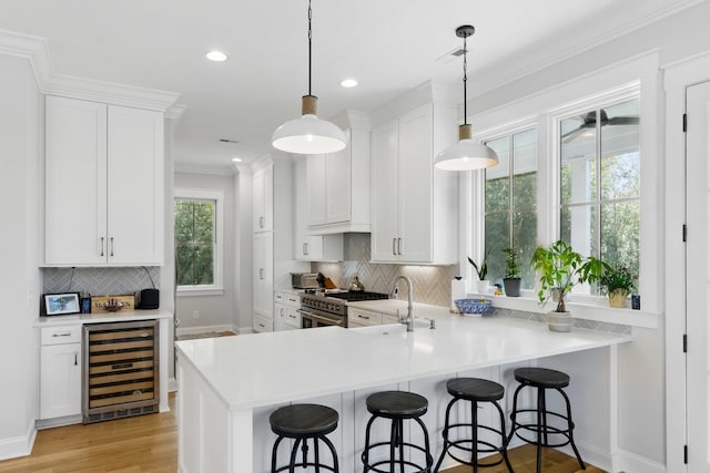 kitchen featuring a breakfast bar, beverage cooler, tasteful backsplash, a sink, and high end stainless steel range oven