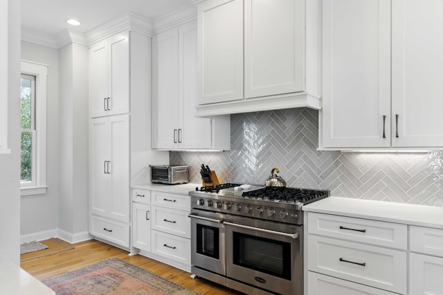kitchen featuring backsplash, range with two ovens, light countertops, white cabinets, and light wood finished floors