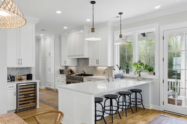kitchen with high end stainless steel range oven, a sink, light countertops, beverage cooler, and light wood-style floors