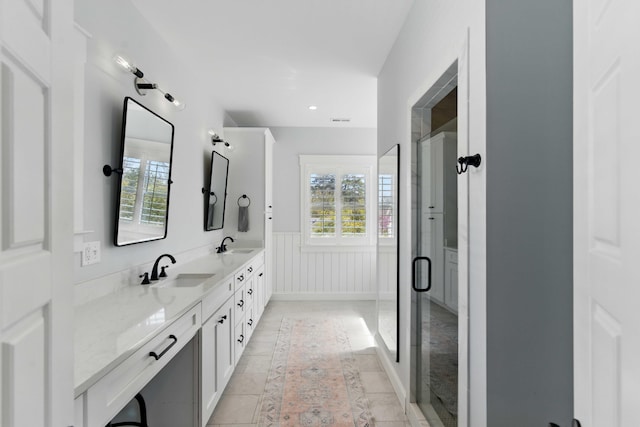 bathroom with double vanity, wainscoting, a sink, and a stall shower