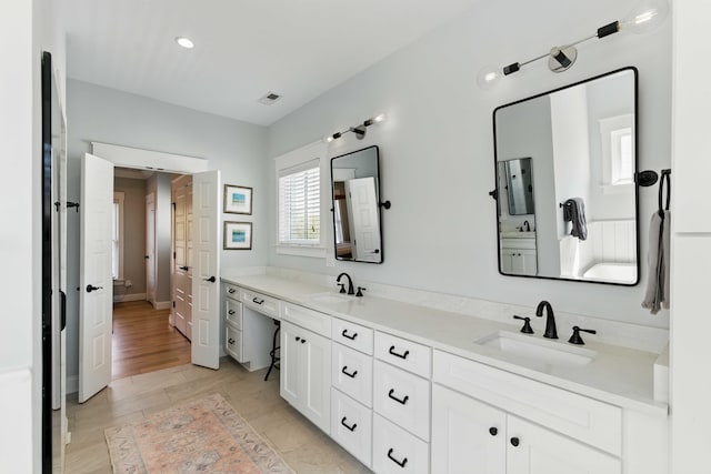 full bath with a sink, recessed lighting, double vanity, and visible vents