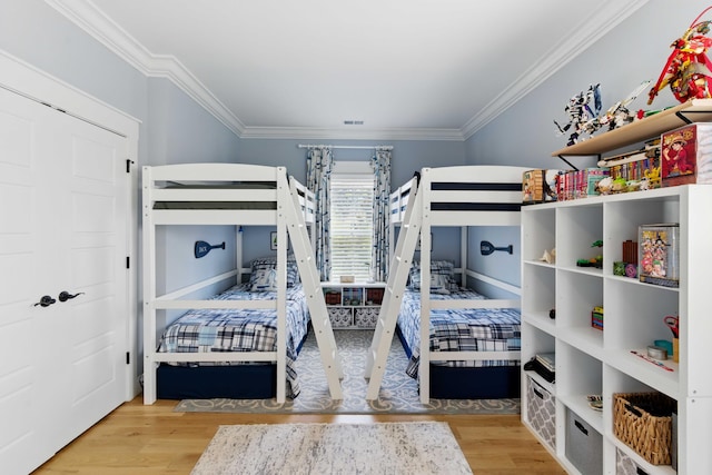 bedroom featuring visible vents, ornamental molding, and wood finished floors
