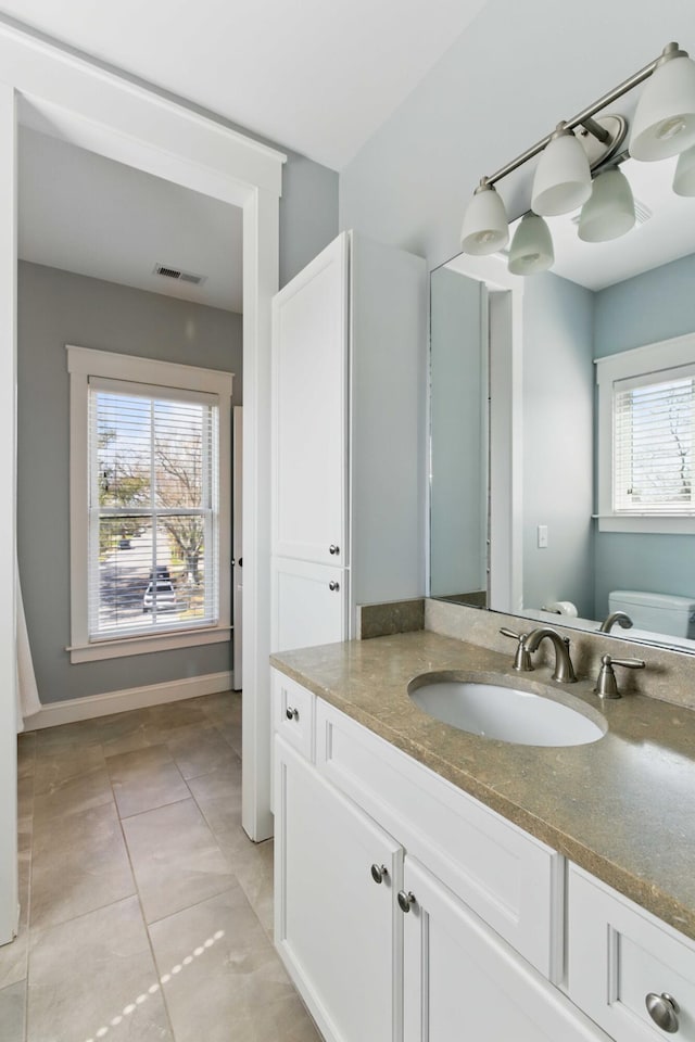 bathroom featuring vanity, visible vents, toilet, baseboards, and tile patterned floors