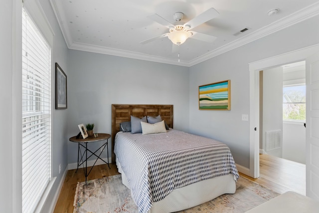 bedroom featuring crown molding, baseboards, visible vents, and wood finished floors