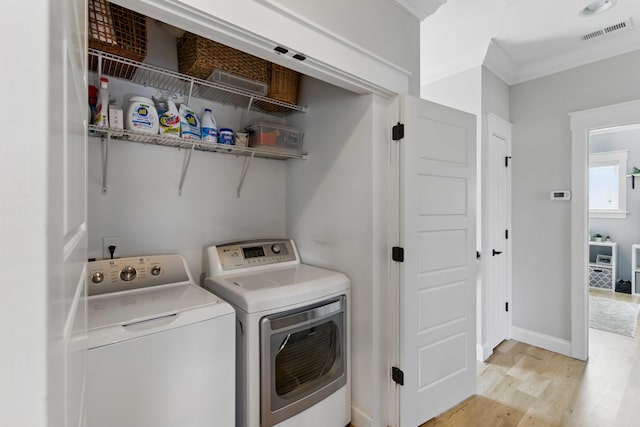 washroom featuring laundry area, crown molding, visible vents, washing machine and clothes dryer, and light wood finished floors