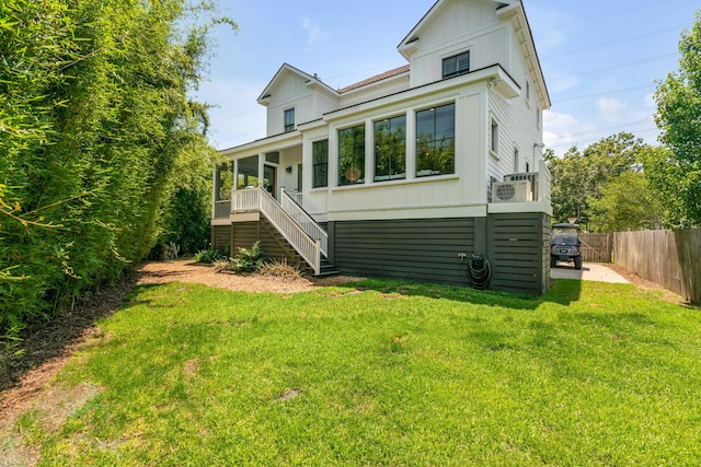rear view of house featuring stairs, board and batten siding, fence, and a yard