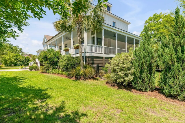 view of side of property with a ceiling fan, a sunroom, and a yard
