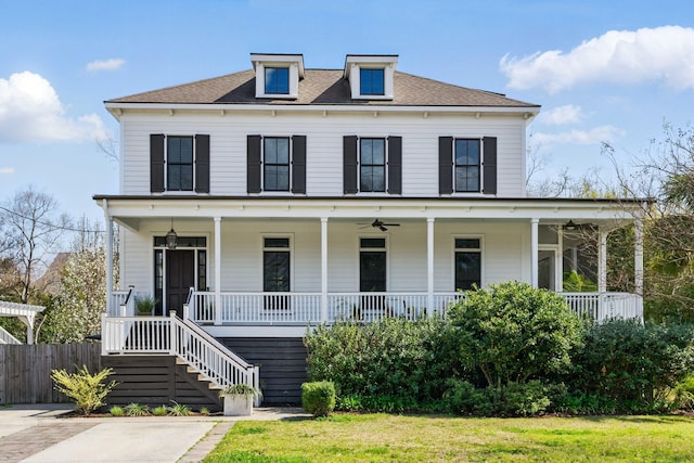 view of front of house with fence, a porch, stairway, a front yard, and a ceiling fan
