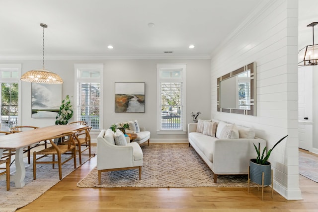 living room with crown molding, a chandelier, wood finished floors, and a wealth of natural light