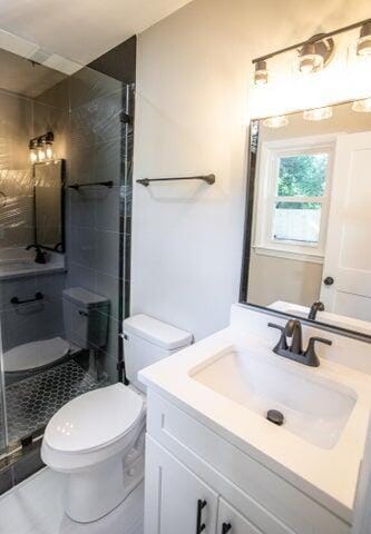 bathroom with tile patterned floors, vanity, toilet, and a shower with door