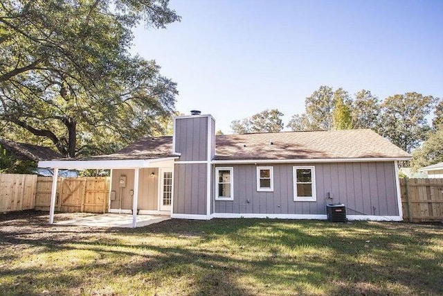 back of house with central AC unit and a lawn