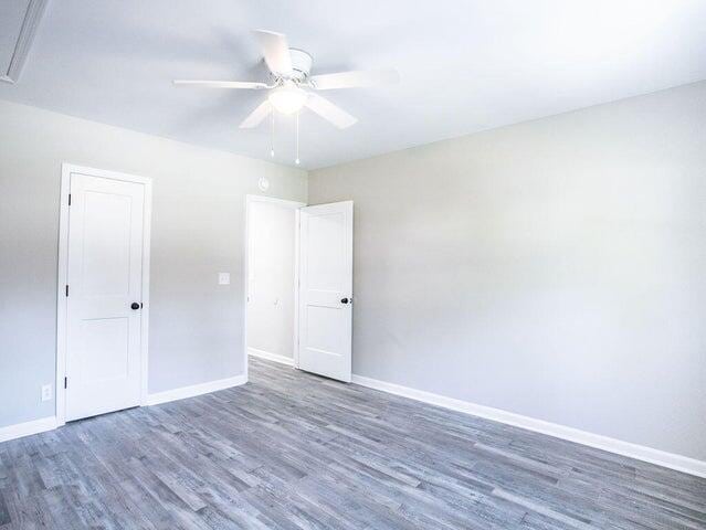 unfurnished room with dark wood-type flooring and ceiling fan