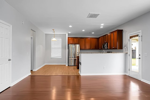 kitchen with hanging light fixtures, light hardwood / wood-style floors, a healthy amount of sunlight, and appliances with stainless steel finishes