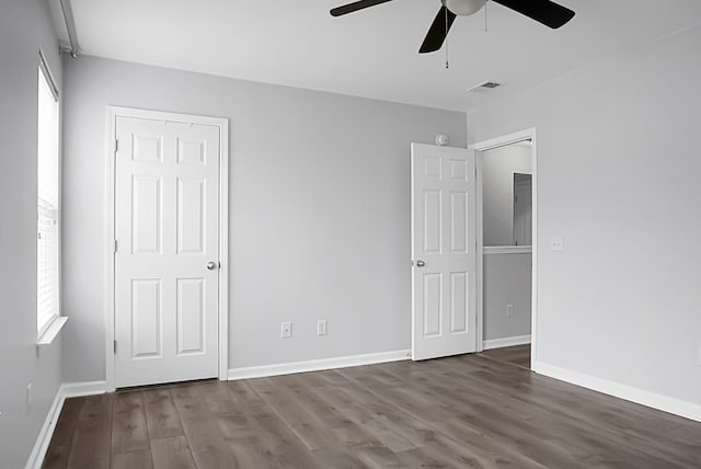 unfurnished bedroom featuring multiple windows, hardwood / wood-style flooring, and ceiling fan