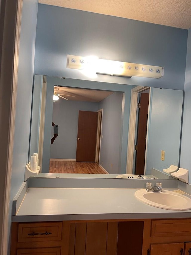 bathroom featuring hardwood / wood-style flooring, ceiling fan, vanity, and a textured ceiling