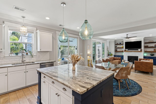 kitchen featuring tasteful backsplash, a sink, a large fireplace, light stone countertops, and visible vents