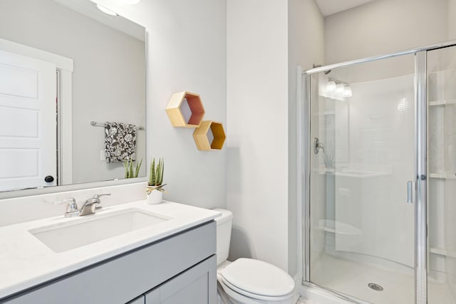 bathroom featuring a shower stall, toilet, and vanity