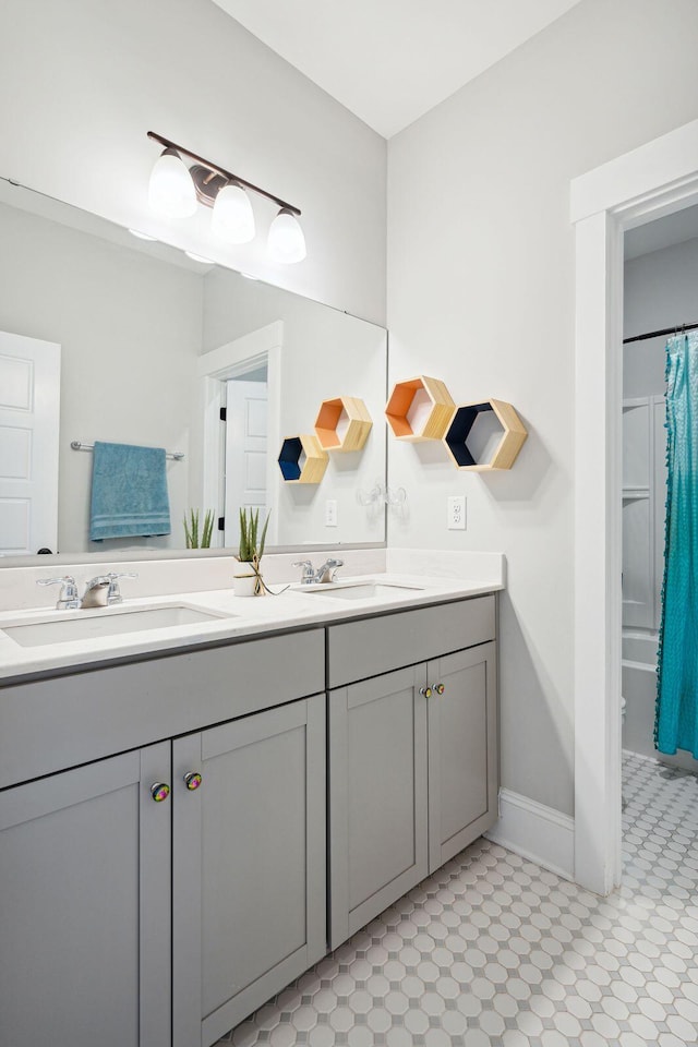 bathroom featuring baseboards, a sink, and double vanity