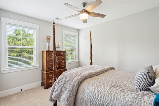 bedroom with light colored carpet, ceiling fan, baseboards, and visible vents