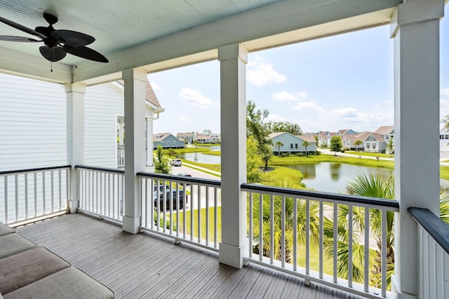 balcony featuring a residential view, a ceiling fan, and a water view