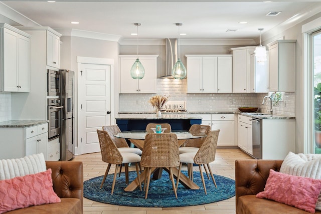 kitchen with light stone counters, visible vents, a sink, wall chimney exhaust hood, and appliances with stainless steel finishes