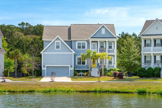 view of front facade featuring a front lawn, an attached garage, a water view, and a balcony