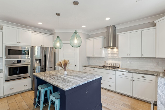 kitchen with stainless steel appliances, a center island, white cabinetry, wall chimney range hood, and wood tiled floor