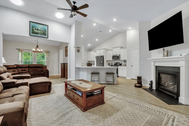 living room featuring ceiling fan with notable chandelier, high vaulted ceiling, and light hardwood / wood-style floors