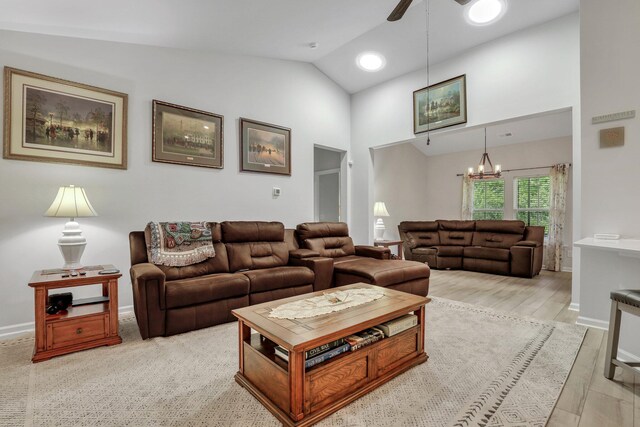 living room featuring ceiling fan with notable chandelier, high vaulted ceiling, and light hardwood / wood-style floors