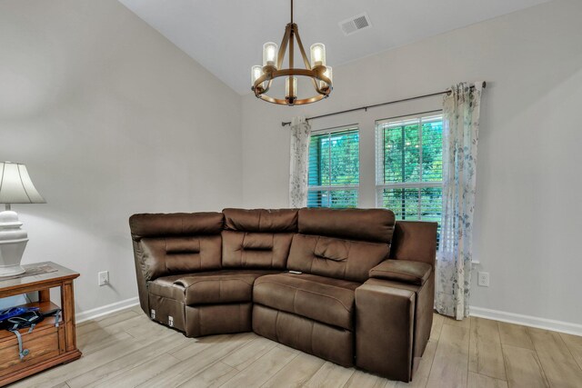 living room with vaulted ceiling, an inviting chandelier, and light hardwood / wood-style floors