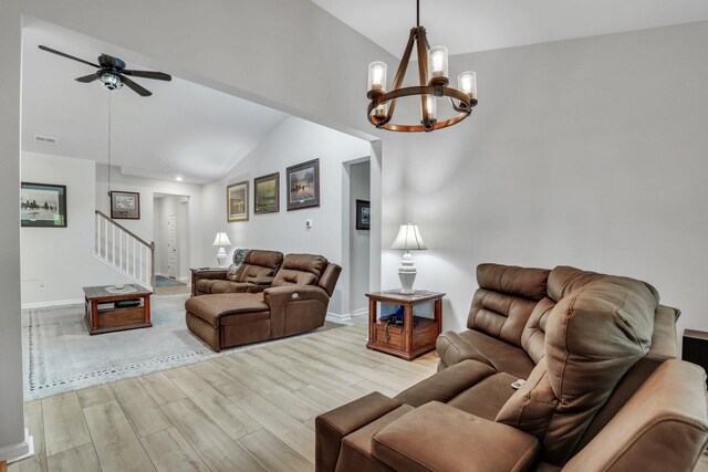 living room with ceiling fan with notable chandelier, light wood-type flooring, and vaulted ceiling