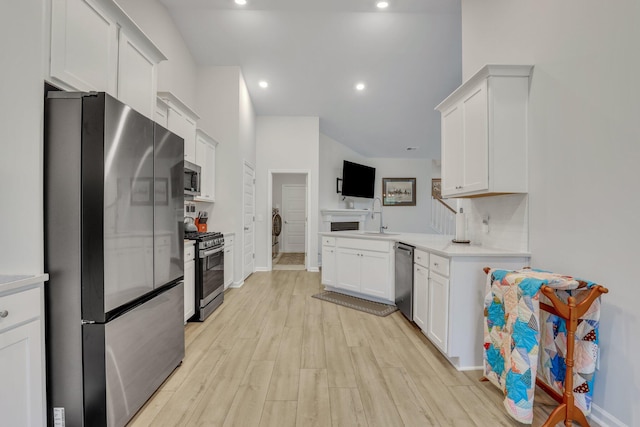 kitchen with white cabinets, light wood-type flooring, appliances with stainless steel finishes, sink, and tasteful backsplash