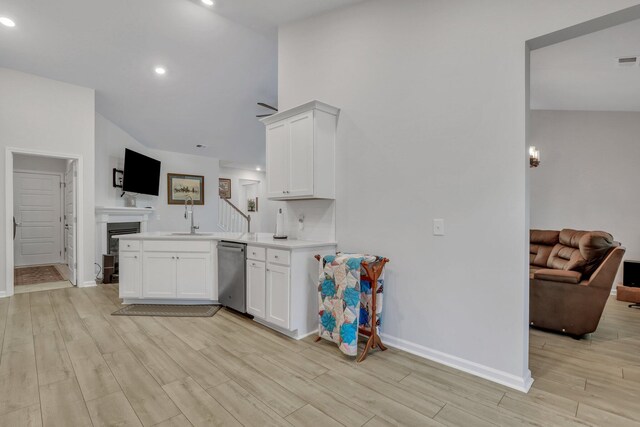 kitchen featuring light wood-type flooring, kitchen peninsula, white cabinetry, and stainless steel dishwasher