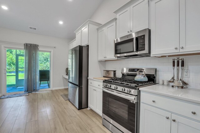 kitchen featuring white cabinetry, light stone counters, decorative backsplash, appliances with stainless steel finishes, and light hardwood / wood-style floors