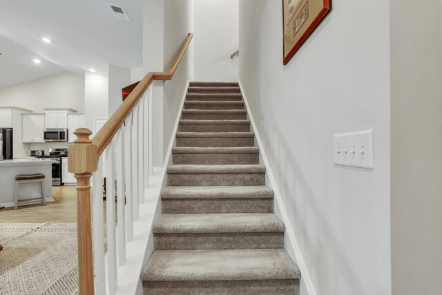 staircase featuring lofted ceiling and hardwood / wood-style floors