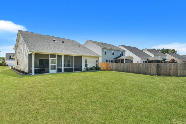 rear view of property with a lawn and a sunroom