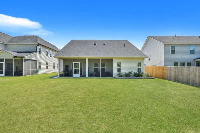 rear view of house with a yard and a sunroom