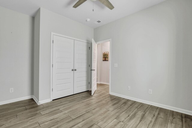 unfurnished bedroom featuring ceiling fan, a closet, and light hardwood / wood-style floors