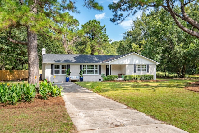 ranch-style house featuring brick siding, fence, driveway, a front lawn, and a chimney