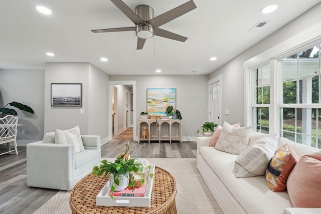 living room featuring baseboards, visible vents, wood finished floors, and recessed lighting