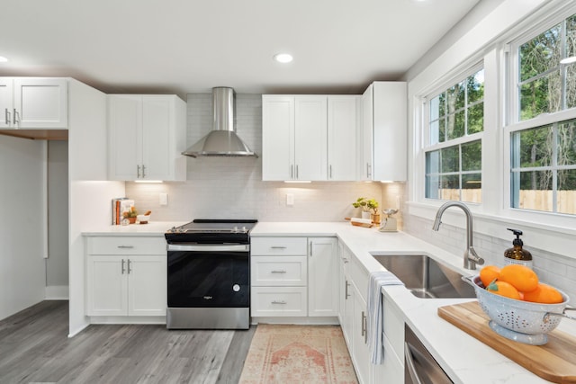 kitchen featuring stainless steel appliances, white cabinets, and wall chimney range hood