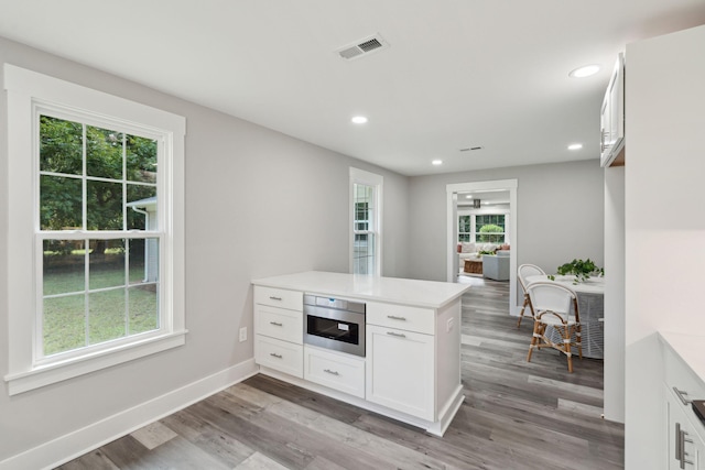 kitchen with light countertops, visible vents, white cabinetry, a peninsula, and baseboards