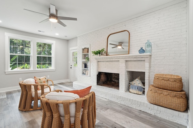 living room with a ceiling fan, a fireplace, baseboards, and wood finished floors