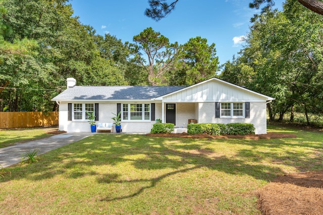 ranch-style home with brick siding, a chimney, fence, board and batten siding, and a front yard